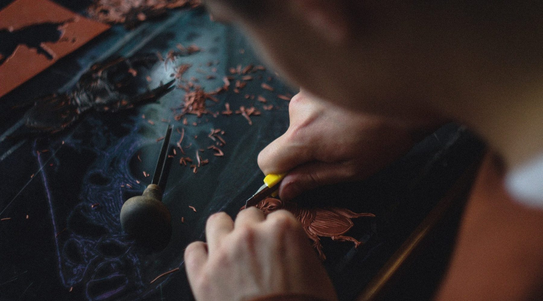 A goldsmith at the bench, the work held over the bench pin.