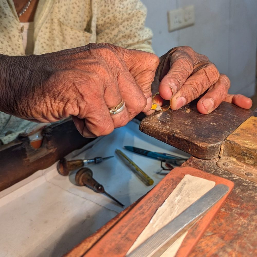 A goldsmith at the bench, the work held over the bench pin.