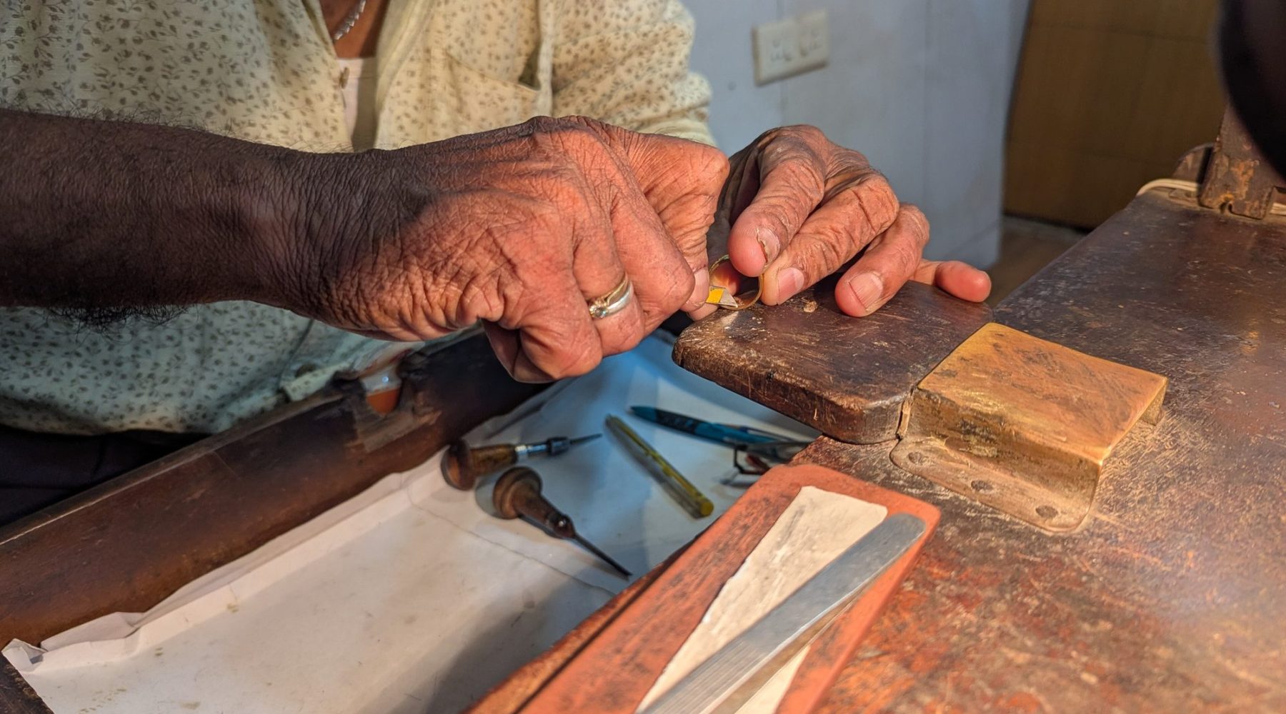 A goldsmith at the bench, the work held over the bench pin.