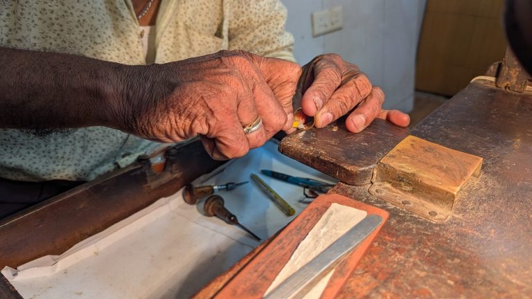 A goldsmith at the bench, the work held over the bench pin.