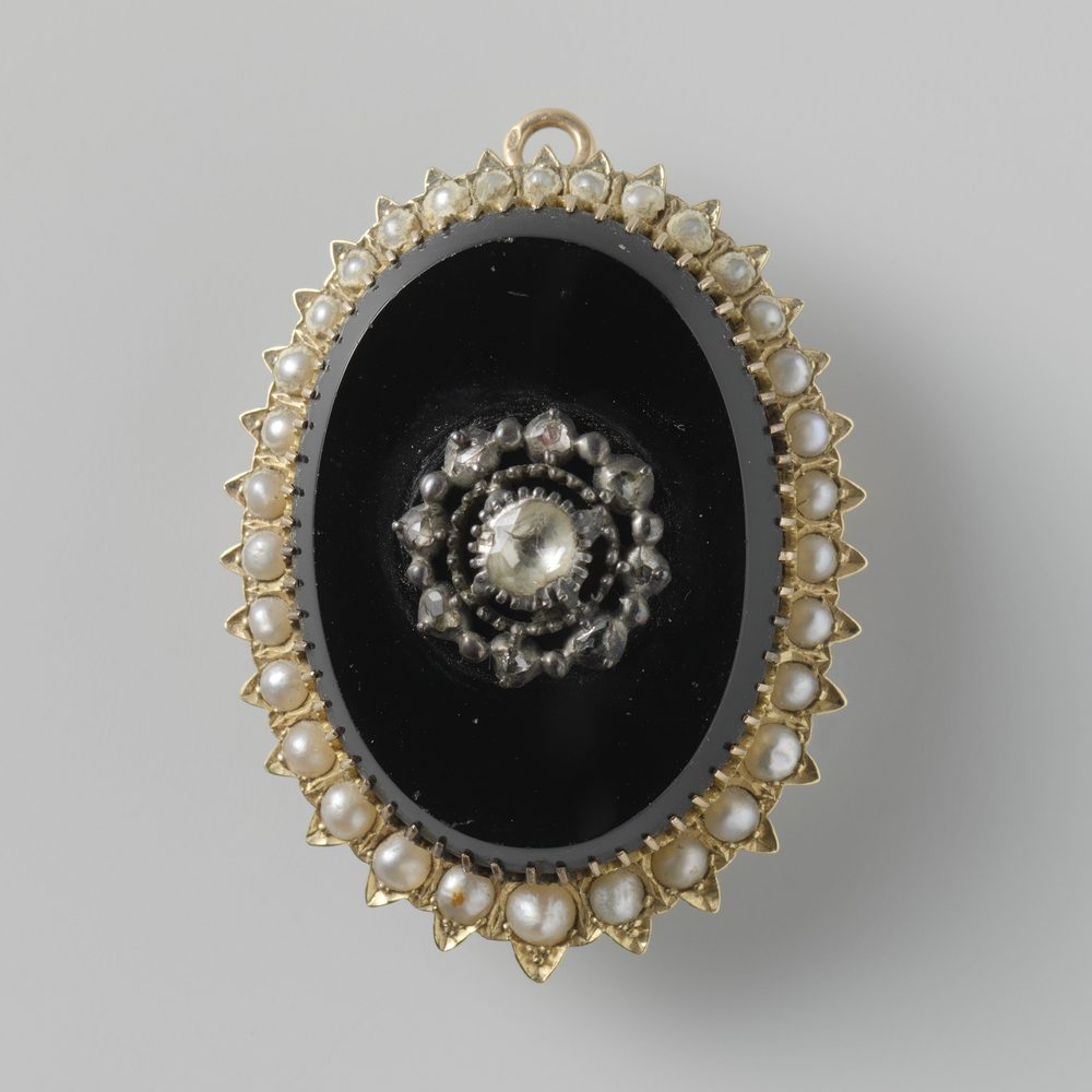 A brooch lying face up, the pin folded flat beneath it.