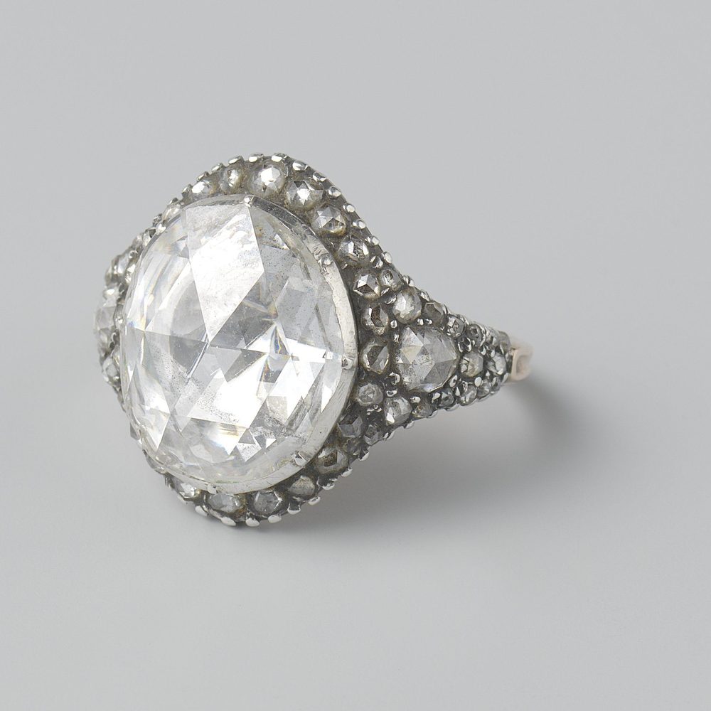 A single round brilliant held in four claws above a plain band.